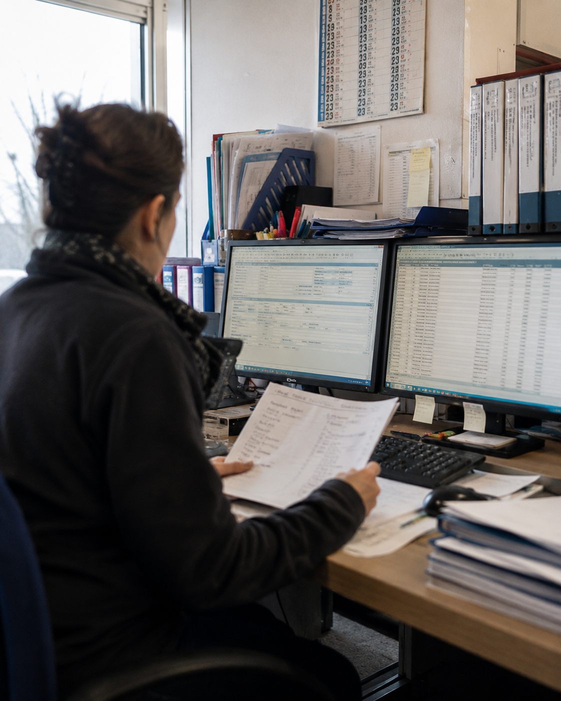 Addetta all'ufficio ordini davanti a due monitor con le righe d'ordine